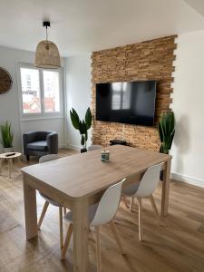 - un salon avec une table et une télévision sur un mur en briques dans l'établissement Le Zen - Wifi - Netflix - 3 chambres - Parking, à Clermont-Ferrand