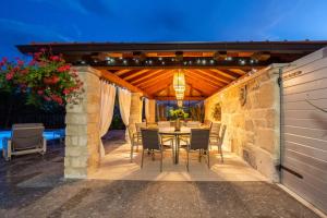 a patio with a table and chairs under a pergola at Krolo Villa&Wine in Trilj