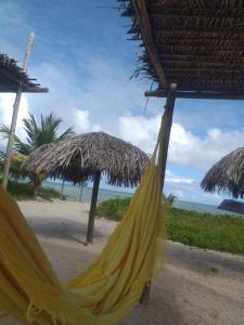 a yellow hammock on a beach with some umbrellas at Hostel e Pousada Maria Bonita in Paripueira