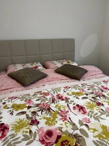 a bed with a floral comforter and two pillows on it at Srnina kuća in Koran