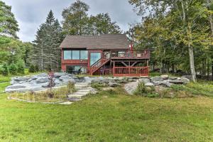 a log home with a deck and a stone wall at Lakefront Catskills Getaway with Private Deck! in Forestburgh