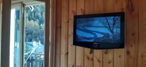 einen Flachbild-TV, der an einer Wand neben einem Fenster hängt in der Unterkunft Maglines in Vars