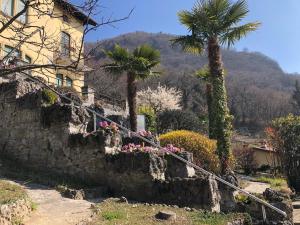 una casa con palme e fiori su un muro di pietra di Villa Silvana a Perledo