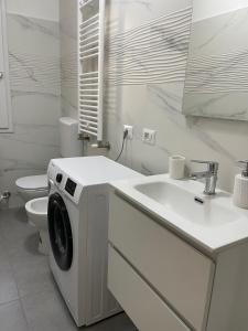 a white bathroom with a washing machine and a sink at Daisy House in Ferrara