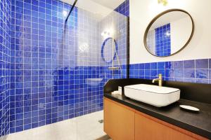 a blue tiled bathroom with a sink and a mirror at Superbe Appartement - Père Lachaise in Paris