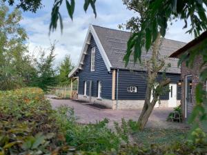 een zwart huis met een gambrel dak bij De Porrel Polsbroek Unit met Privé Jacuzzi, Spa en Sauna in Polsbroek