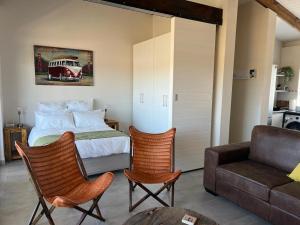 a bedroom with a bed and two chairs and a couch at Kabeljauws Beach Estate in Jeffreys Bay