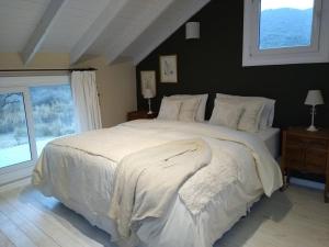 a bedroom with a large white bed with a window at Chacra La Invernada Pequeño Hotel de Campo in Villa Giardino