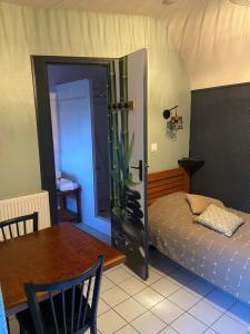 a bedroom with a bed and a table and a door at La Pénate in Pluduno