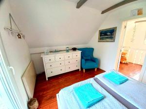 um quarto com uma cama, uma cómoda e uma cadeira azul em Honey hill apartment Fruska Gora em Čerević