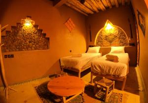 een kamer met twee bedden en een tafel erin bij Auberge Kasbah Dar Sahara Tours in Mhamid