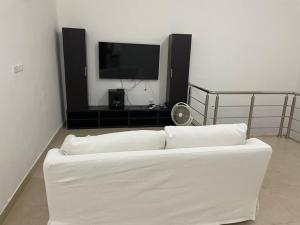a white couch in a living room with a flat screen tv at Al Mattal in Amman