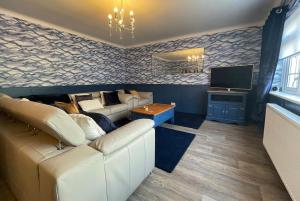 a living room with a couch and a television at Rhoslan. Boutique style farmhouse in Snowdonia in Caernarfon