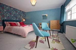 a bedroom with a bed and two blue chairs at Rhoslan. Boutique style farmhouse in Snowdonia in Caernarfon