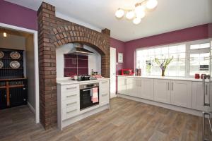 a kitchen with white cabinets and a brick fireplace at Rhoslan. Boutique style farmhouse in Snowdonia in Caernarfon