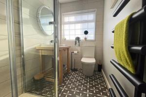 a bathroom with a toilet and a sink and a mirror at Rhoslan. Boutique style farmhouse in Snowdonia in Caernarfon +13 photos