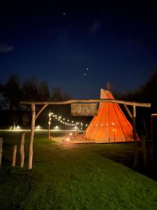 una tienda naranja en un campo por la noche en Comfort Tipi Marie, Tipi Bo Deluxe & tent Nicolaï - 'Glamping in stijl', en Lembeke