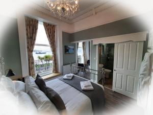 a bedroom with a large bed and a chandelier at Highlander House B&B in Rothesay