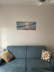 a blue couch in a living room with two paintings on the wall at Appartamento ' Il sole di Vale' in Loano