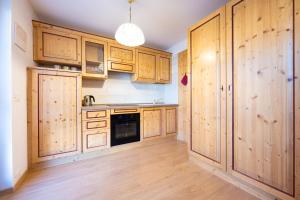 a kitchen with wooden cabinets and wooden floors at Cesa te Val in Vigo di Fassa