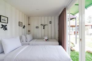 two beds in a room with white walls at Container Smart Stay CSS in Bedugul