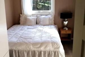 a bed with white sheets and pillows next to a window at peaceful place in Hønefoss