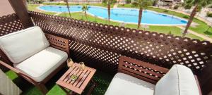 雷塔馬爾的住宿－Ático de ensueño, El Toyo, Almería - Playas, Golf, Cabo de Gata，一个带两把椅子和一张桌子的阳台以及一个游泳池