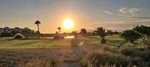 zachód słońca nad polem golfowym z palmami w obiekcie Ático de ensueño, El Toyo, Almería - Playas, Golf, Cabo de Gata w mieście Retamar