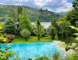 una piscina en un jardín con un lago en el fondo en 5 bedrooms house with lake view shared pool and enclosed garden at Santa Cruz do Douro 1 km away from the beacha en Santa Cruz do Douro