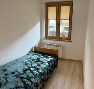 a small bedroom with a bed and a window at Apartament Kaspruś in Zakopane