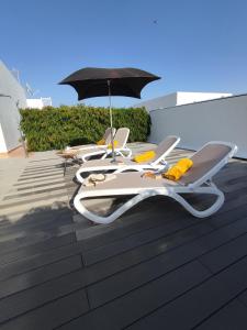 three lounge chairs and an umbrella on a deck at Casa Bermeja - Tiscamanita in Tiscamanita