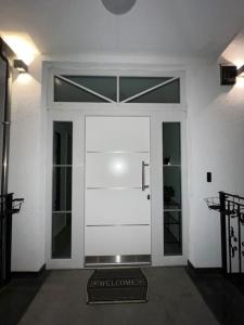 a white door with a welcome sign in front of it at Luxus-Doppelhaushälfte im ruhigen Blumenviertel in Berlin