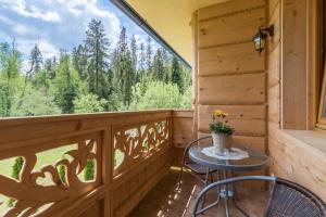 porche con mesa, sillas y ventana grande en Gościniec Nad Potokiem, en Małe Ciche