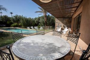 a patio with a table and chairs and a pool at Villa Mayaz - Piscine chauffée in Marrakech