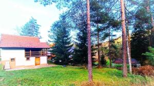 una pequeña casa blanca en un patio con árboles en Vikendica Boki i Maki en Divčibare