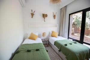 two beds in a room with a window at Villa Mayaz - Piscine chauffée in Marrakech