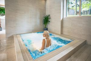 una mujer sentada en una bañera en una piscina en Villa Cannes Resort Zakopane - grota solna, sauna fińska en Zakopane