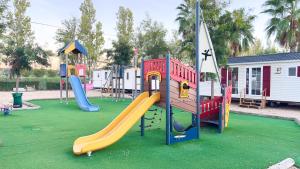 a playground with several slides on a green field at Mobil-Home Les Lauriers Roses Camping Siblu 4**** in Fréjus