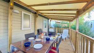 a table and chairs on a porch with a wooden deck at Mobil-Home Les Lauriers Roses Camping Siblu 4**** in Fréjus