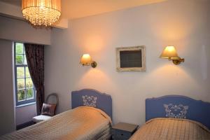 a bedroom with two beds and two lights on the wall at Linnhe in Appin