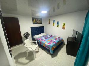 een slaapkamer met een bed, een stoel en een televisie bij Casa Olimpico Hostal in Cali