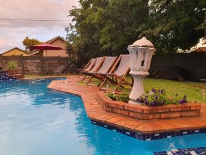 a group of chairs and a swimming pool with a bird bath at Horizon Green Guest House in Randfontein