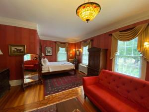 a living room with a red couch and a bed at Historic Rosemont Manor in Berryville