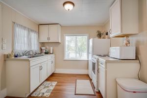 a kitchen with white cabinets and a sink and a window at Lakeshore Fishing Cabins All 6 cabins in Lake Ozark