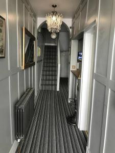 a hallway with a staircase with a chandelier and a stair case at The Willows in Brighton & Hove