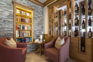 une bibliothèque avec deux chaises et une table avec des livres dans l'établissement Superior Hotel Panorama, à Obertauern