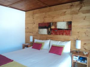 a bedroom with a white bed with a wooden wall at Hoteles Pueblo de Tierra in San Pedro de Atacama