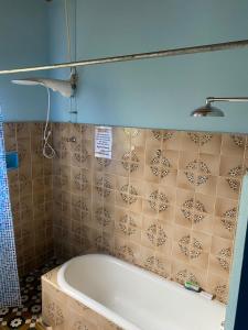 ein Bad mit einer Badewanne und einer gefliesten Wand in der Unterkunft Casa estilo colonial, no Centro de Aiuruoca-MG. in Aiuruoca