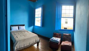 Habitación azul con cama y silla en Casa estilo colonial, no Centro de Aiuruoca-MG., en Aiuruoca