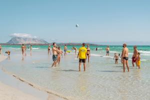 un gruppo di persone in piedi sull'acqua di una spiaggia di Amareclub Le Rose a San Teodoro